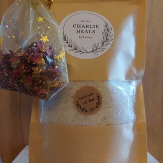 A bag of Healing Muscle Soak with a mesh bag of rose petals attached.