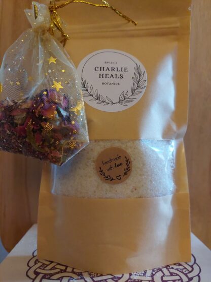 A bag of Healing Muscle Soak with a mesh bag of rose petals attached.